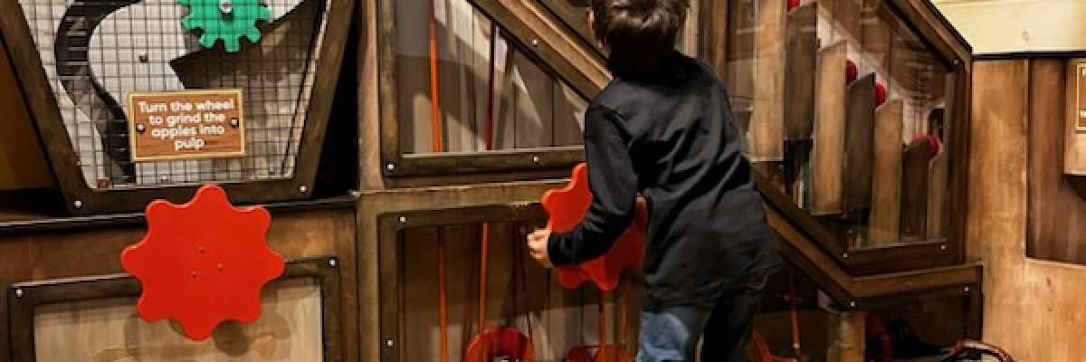 Child looking up at cider mill exhibit.